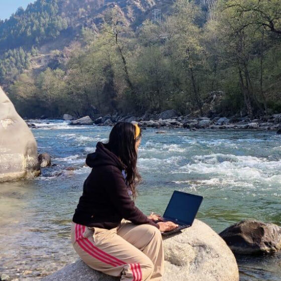 girl working on laptop near river