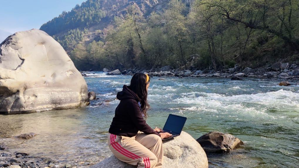 girl working on laptop near river